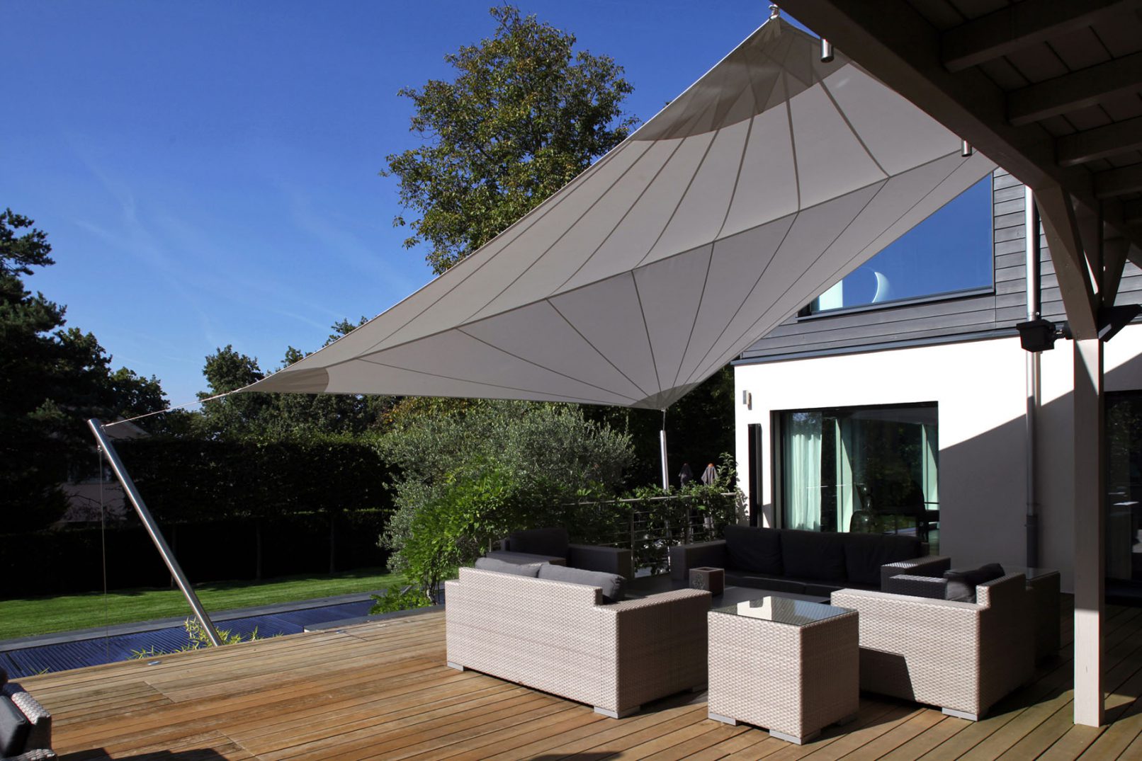 terrasse avec mobilier moderne contemporain et protection solaire avec des voiles de bâteau tendues
