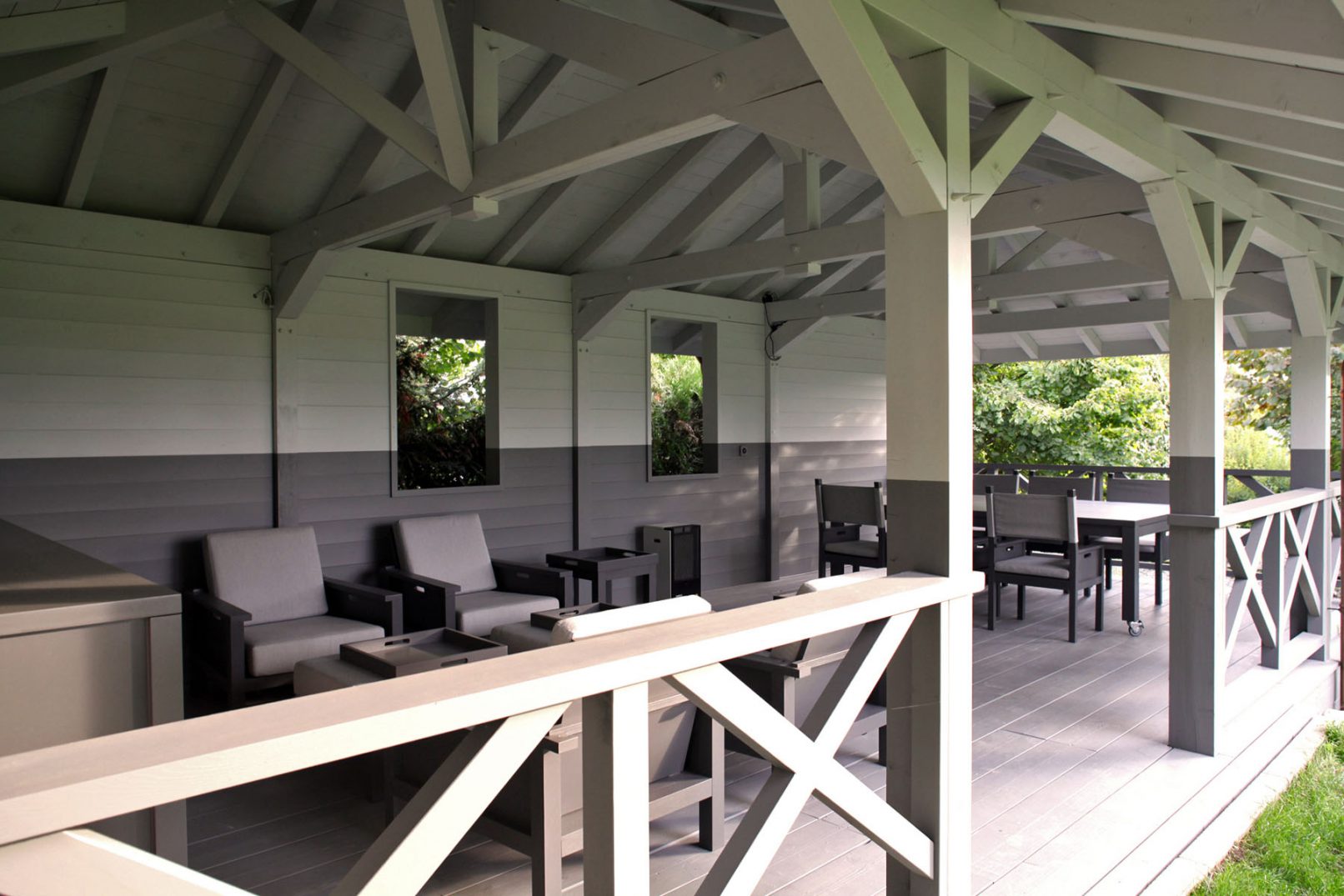 Pavillon d'été dans jardin avec charpente apparente et plancher bois, construction en bois